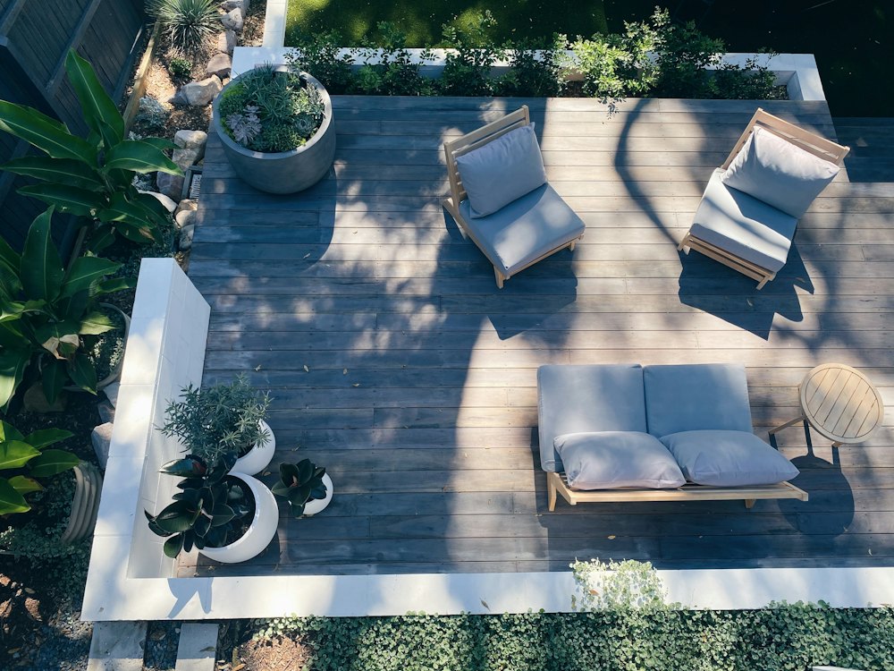 Vue du dessus d'une terrasse en bois avec fauteuils et plantes en pots